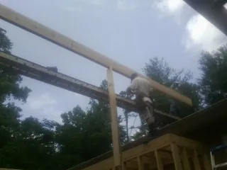 Carpenter setting a ridge beam over a new addition frame — Ice Dam Removal by Roofing Brothers in Sweet Valley