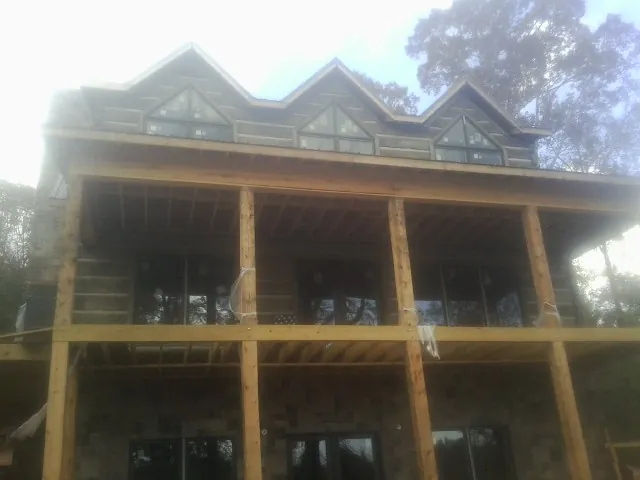 Dormers and porch framing on a large log home under construction — Roof Coating work by our crew in Sweet Valley