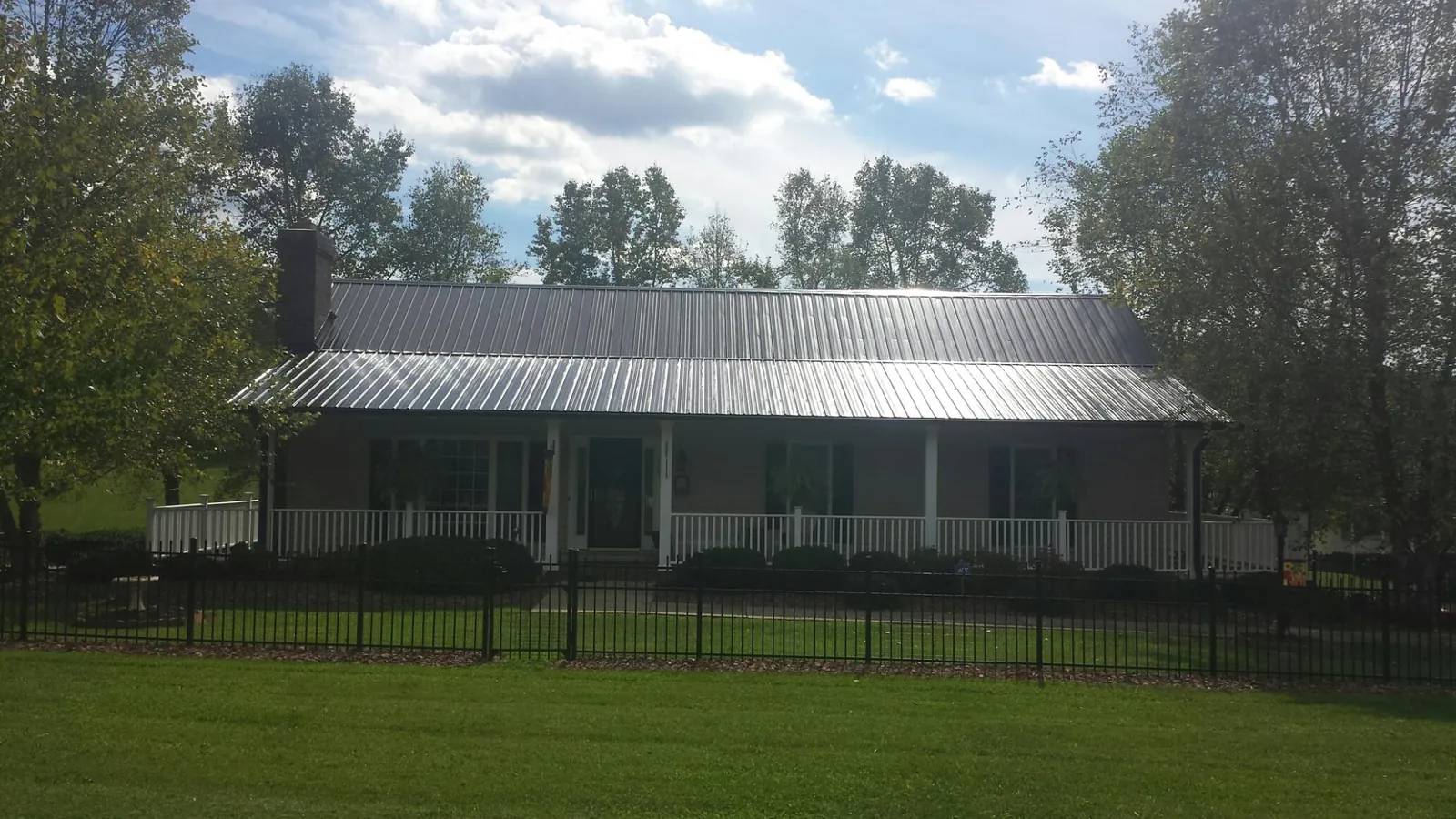 Gray metal roof on a brick ranch with a full width front porch — Gutter Guard Installation work by our crew in Sweet Valley