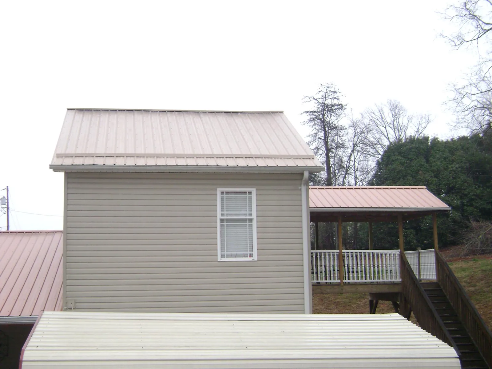 Tan metal roofs on a two story addition and attached porch, from a Roof Replacement job in Sweet Valley