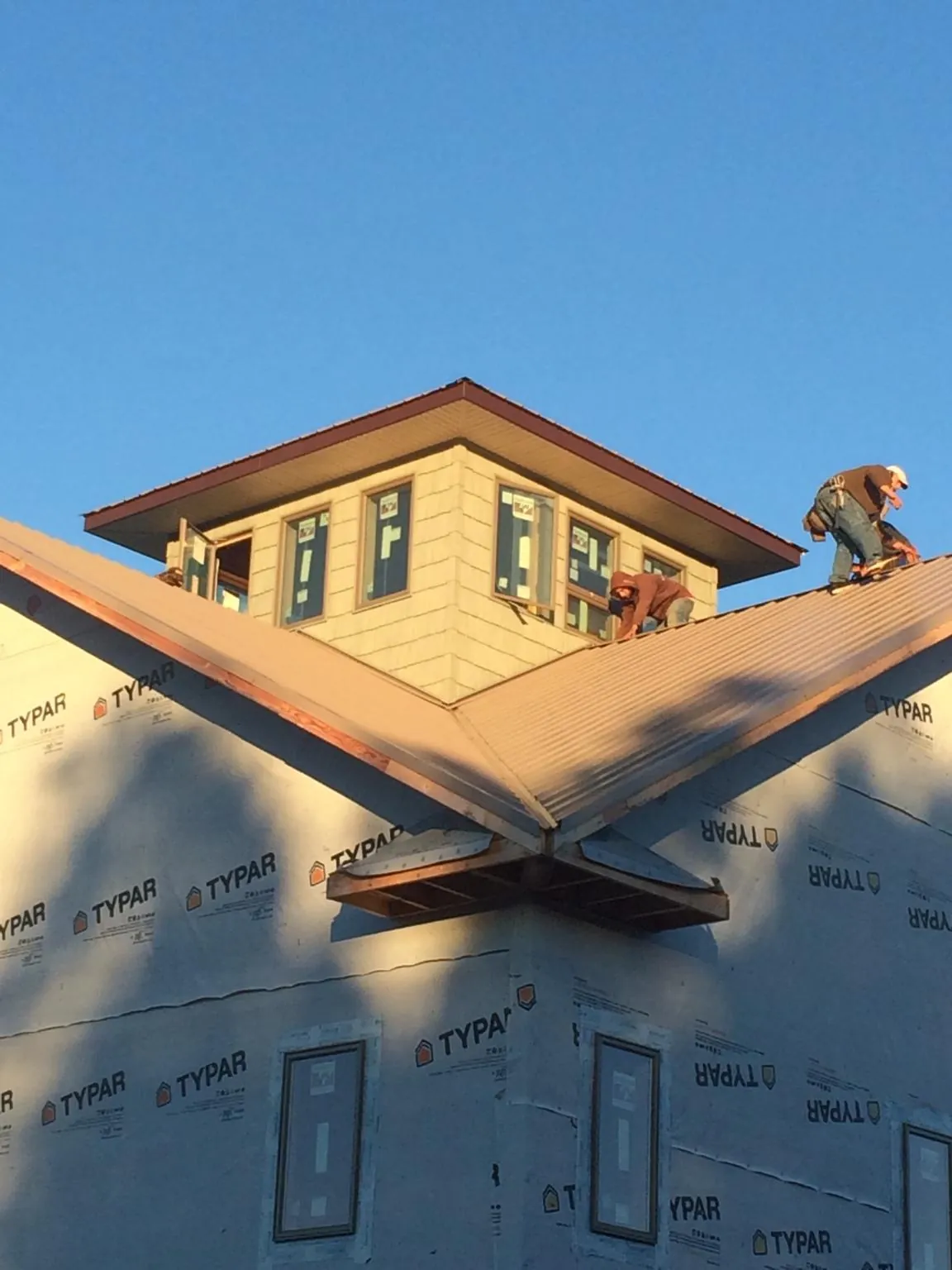 Roofers working around a rooftop cupola on a new metal roof at sunset — Roof Waterproofing in Sweet Valley by Roofing Brothers